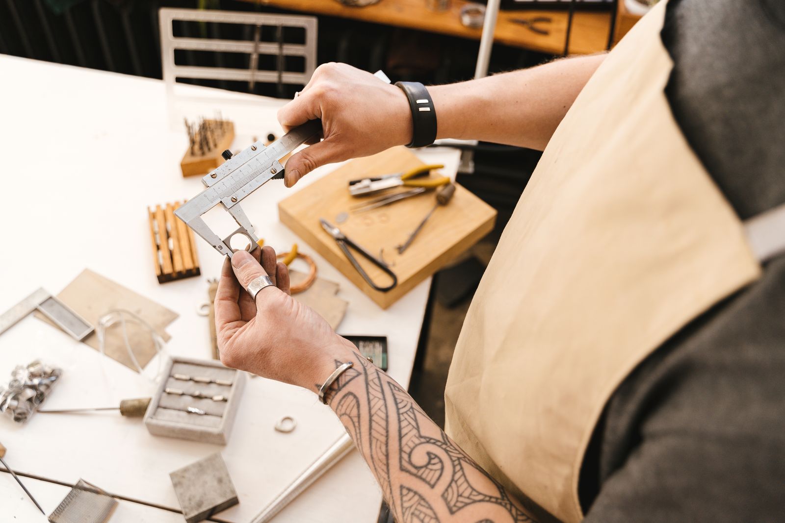 Hands measuring a metal part with a caliper